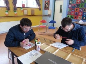 2 students in the Anne Sullivan centre colouring pictures of a flower while wearing adapted glasses that impair vision. 