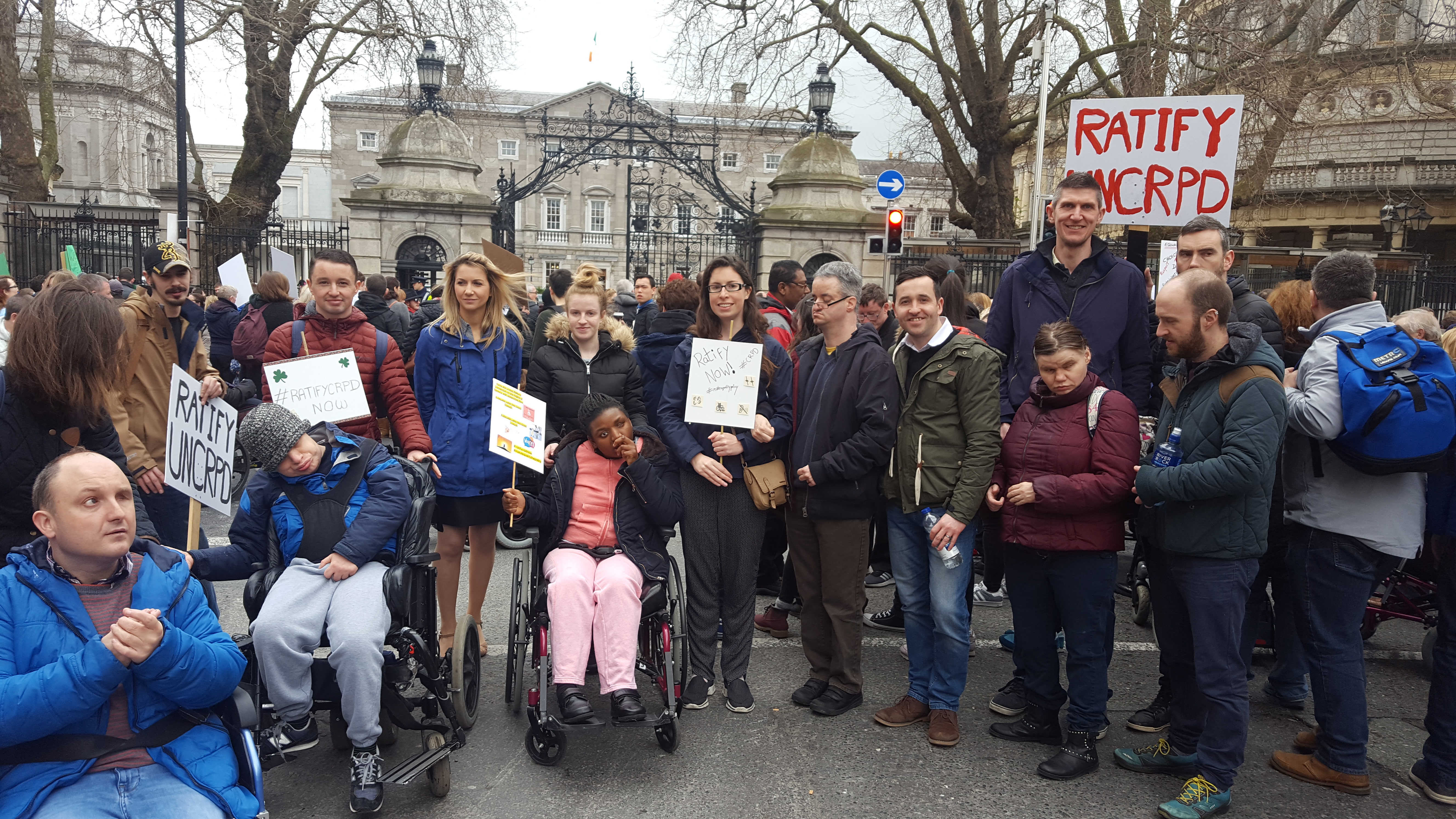 Staff and service users gathered outside government buildings in Dublin, holding signs, at a ratify UNCRPD protest.