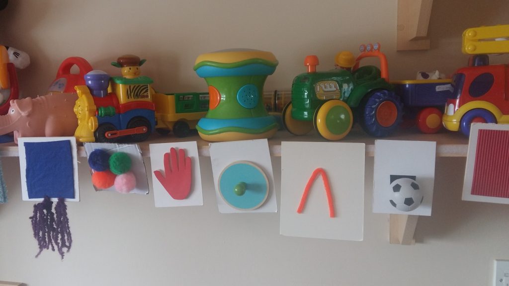 Image of a shelf of toy vehicles and animals and tactile cards hanging from the shelf