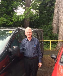 Image of a volunteer driver standing beside one of the Anne Sullivan centre's vehicles