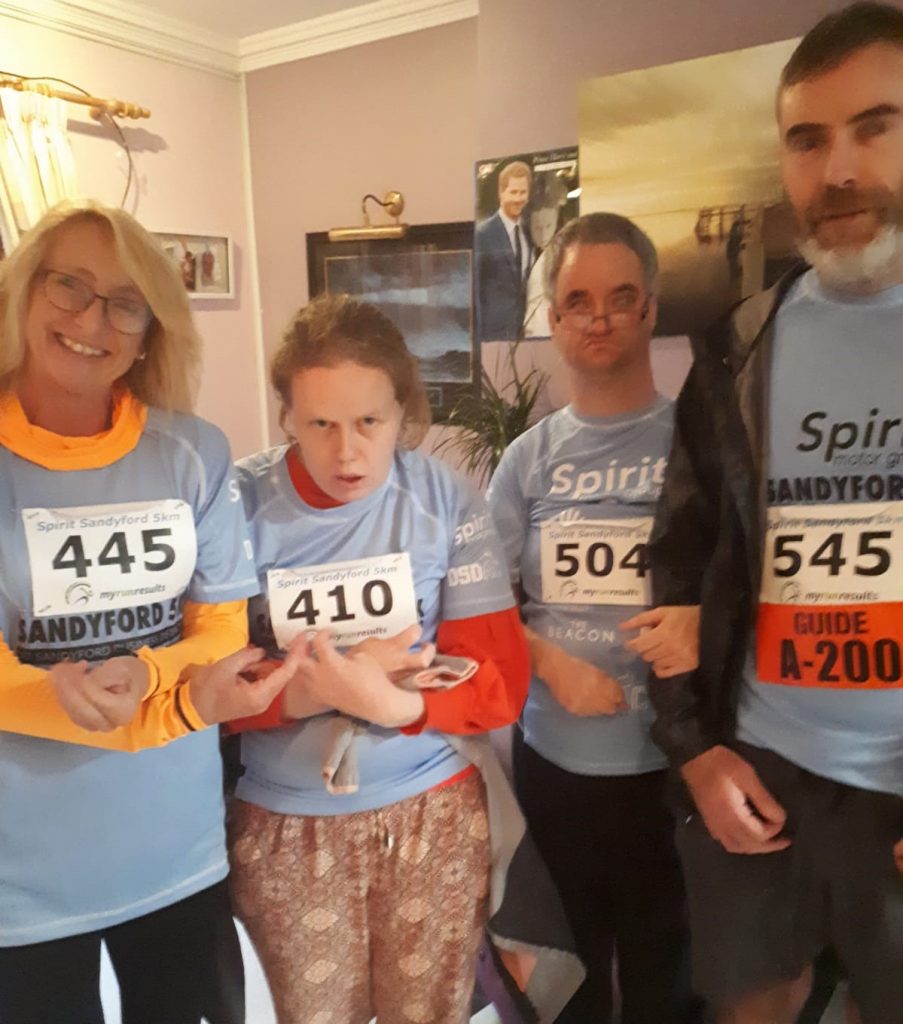 Image of 2 staff and 2 service users wearing sandyford 5k race t shirts.
