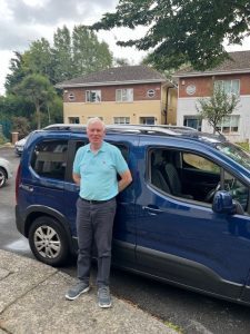 Volunteer driver smiling beside vehicle